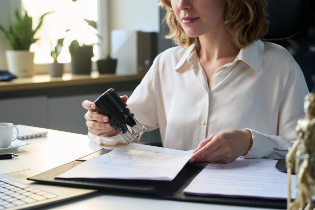 Woman sitting at desk holding a stamp and paperwork