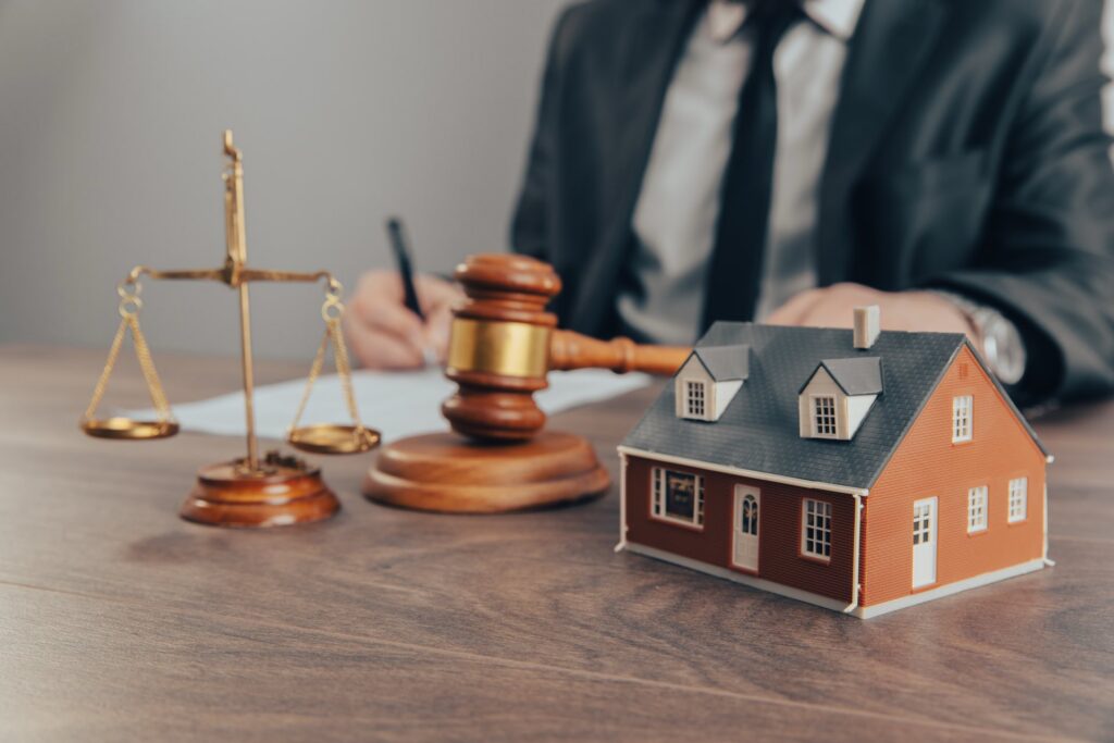 A person sitting at a desk holding a gavel next to a small wooden house