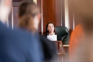 Judge sitting in a chair holding papers looking at other people