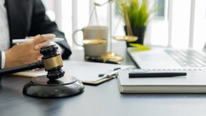 Person sitting at a desk with a gavel, paperwork and a laptop