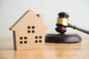 Wooden house on a table next to a gavel