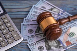 The judge's gavel, calculator, banknotes of American dollars on the background of wooden table.