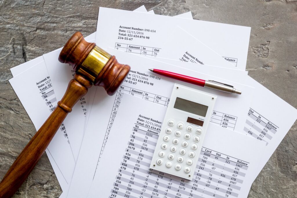 A calculator, pen, and gavel on top of paperwork