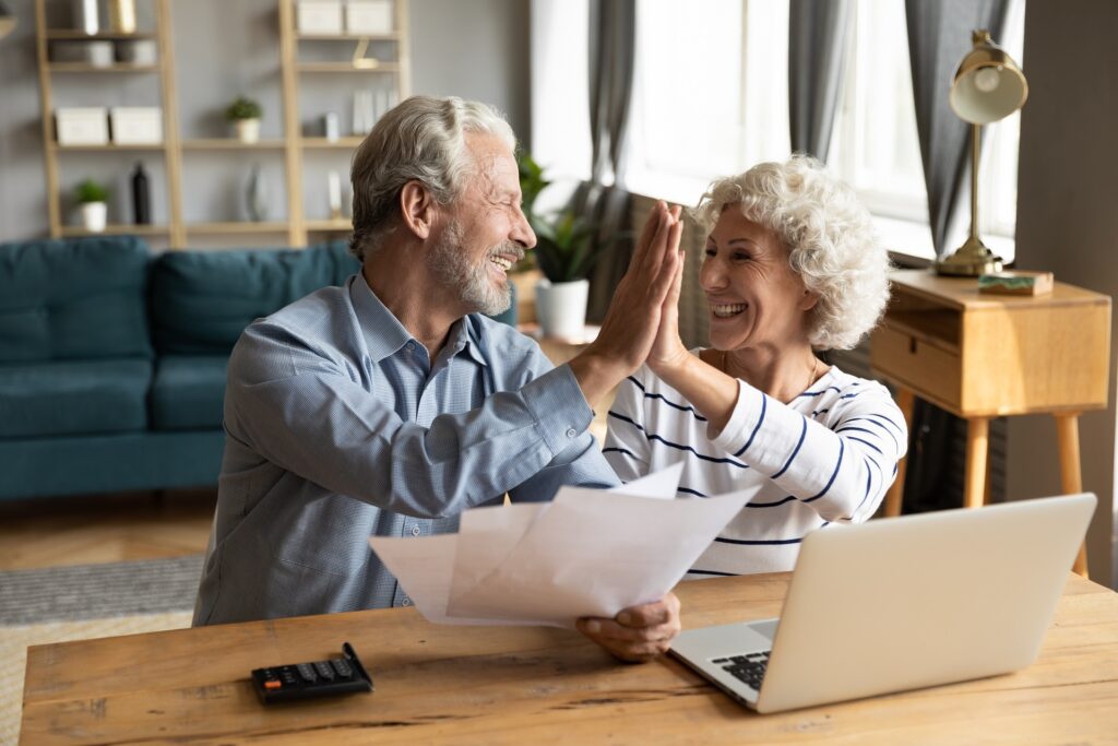 Aged couple giving each other a high five by a laptop on a table | Filing For Bankruptcy | Grady BK