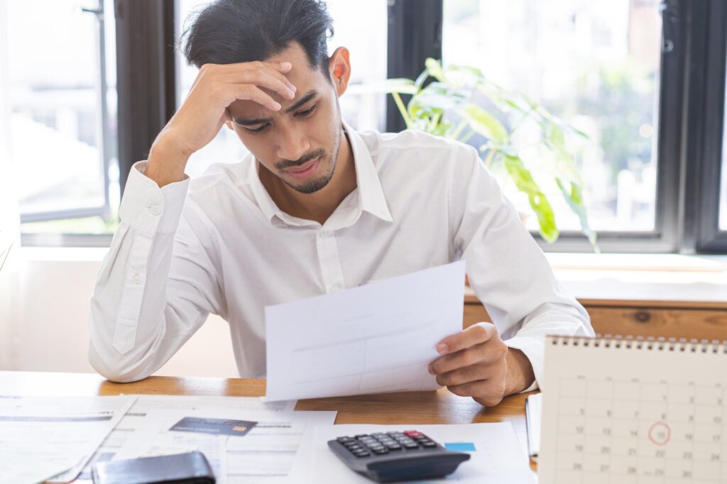 Guy sitting down stressed going over paperwork