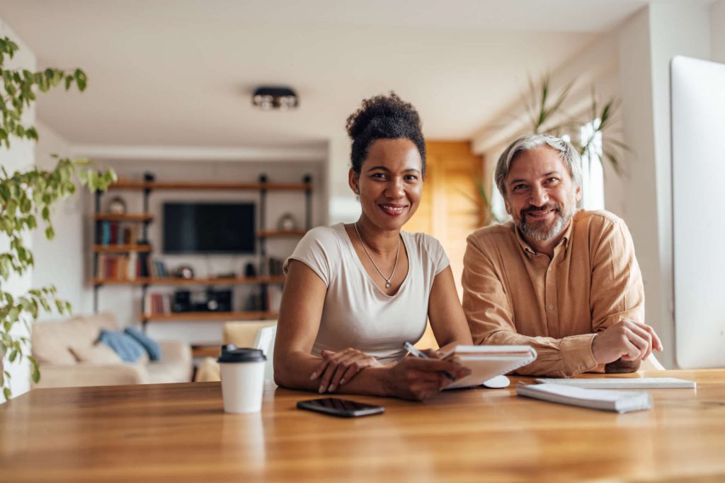 Smiling couple budgeting at large dining table