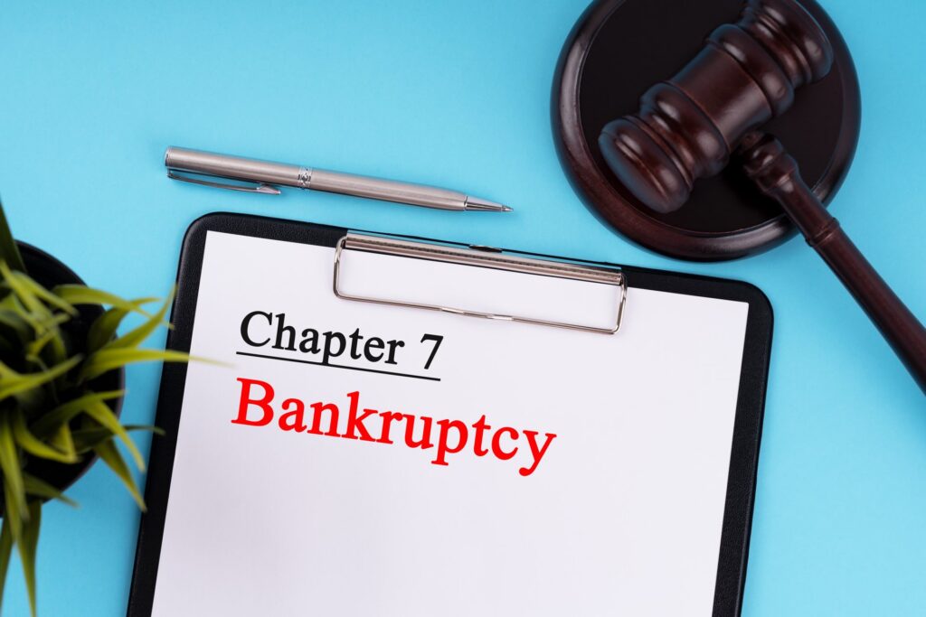 Blue background with a gavel, a pen, and a clipboard that says chapter 7 bankruptcy